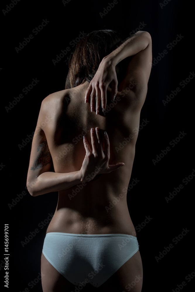 Naklejka premium woman suffers from spine pain, backache standing over black background