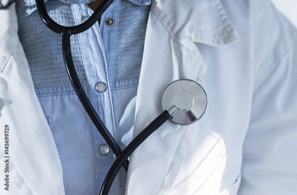 Medical doctor in white gown on white background holding a stethoscope. Focus on the stethoscope. Medical doctor in white gown on white background holding a stethoscope. Focus on the stethoscope.