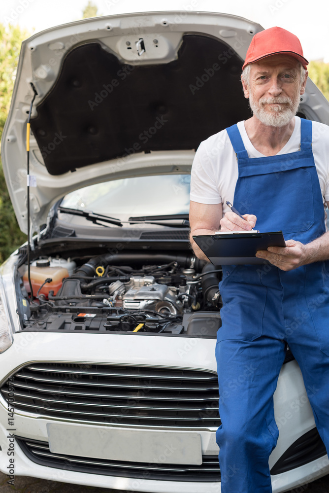 Car mechanic checking a car engine Car mechanic checking a car engine