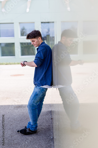 Junger Mann sieht ungeduldig auf die Uhr und wartet photo