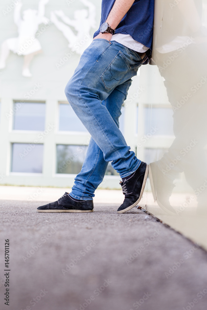 Lässige Haltung gegen Wand in Jeans