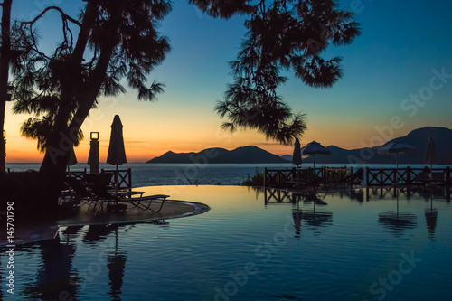 Sunset, beach chairs, infinity swimming pool silhouette