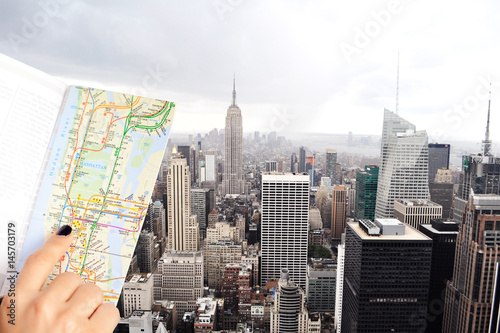 Traveler holding city map in front of Empire State Building, New York City, view from Rockefeller Center