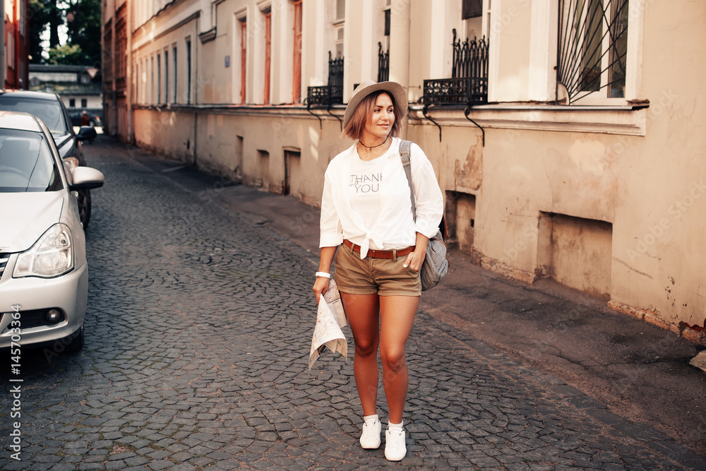 Travel guide. Young female traveler with backpack and with map on the street. Travel concept