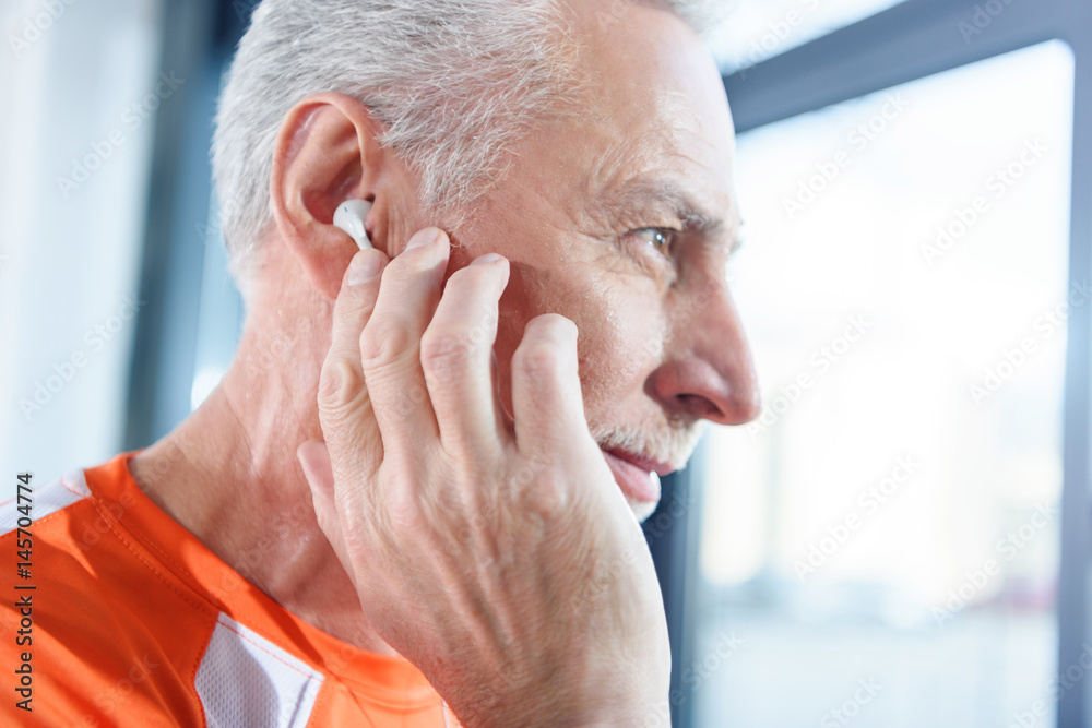 Close-up profile portrait of bearded mature man in earphones looking away Close-up profile portrait of bearded mature man in earphones looking away