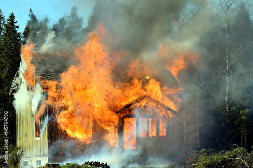 Slika na platnu Home on fire as the flames burst through the windows, door and roof of the house