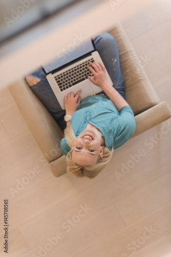 Young woman using laptop at home top view
