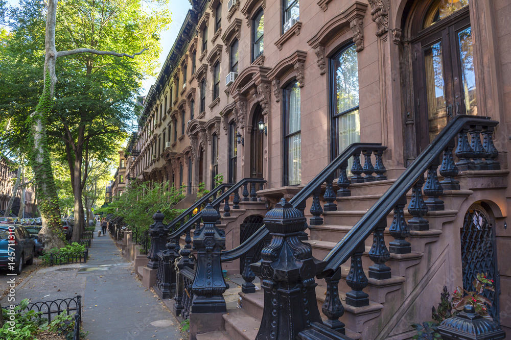 Naklejka premium Sceniczny widok klasyczny Brooklyn brownstone blok z długą fasadą i ozdobnymi przygarbienia balustradami w Miasto Nowy Jork