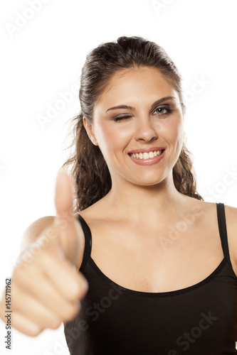 young beautiful brunette showing thumbs up and winking