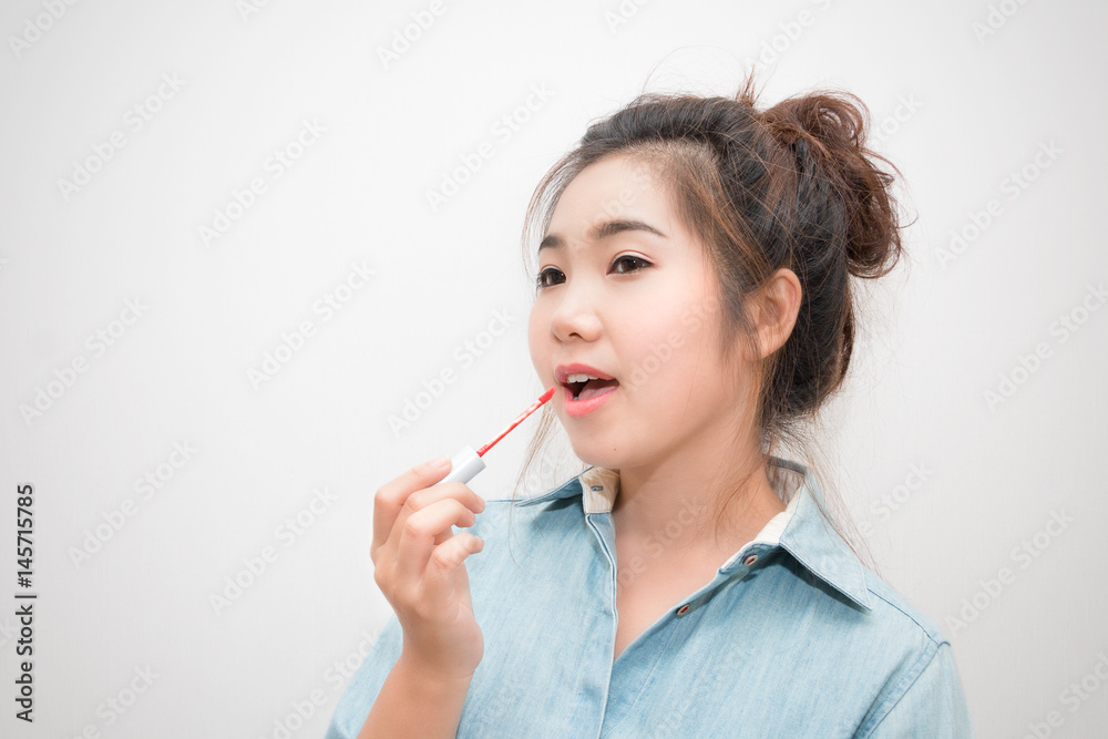 Beautiful asian young woman doing makeup using a lip gloss Beautiful asian young woman doing makeup using a lip gloss