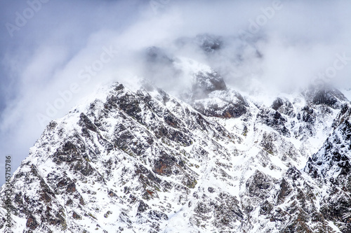 Beautiful dramatic snowy mountain peaks in clouds. Scenic winter landscape © Wilding