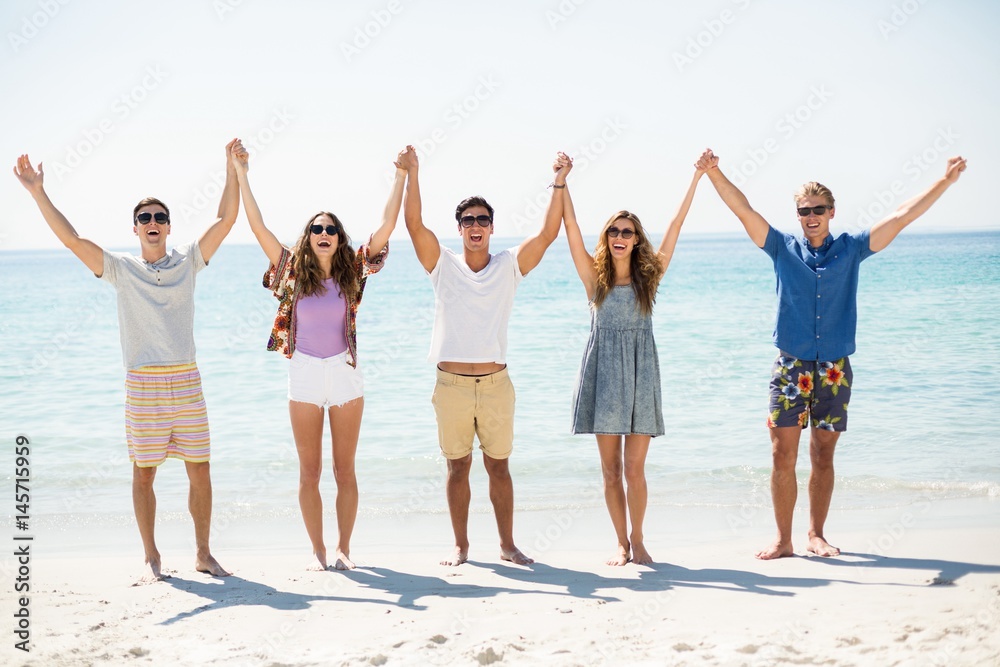 Obraz premium Happy friends with arms raised at beach