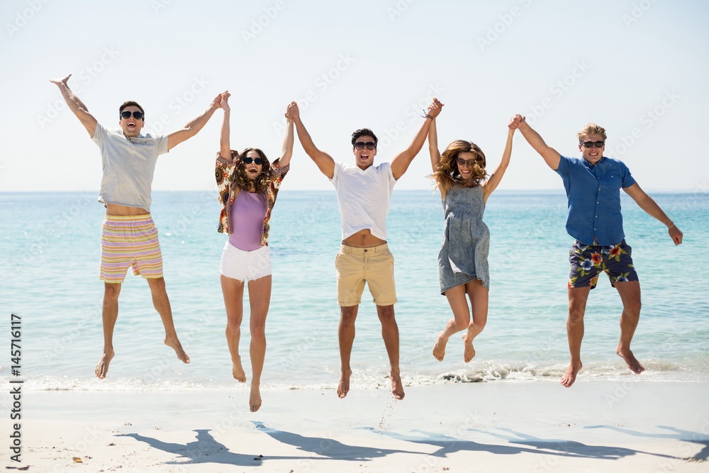 Friends jumping with arms raised at beach