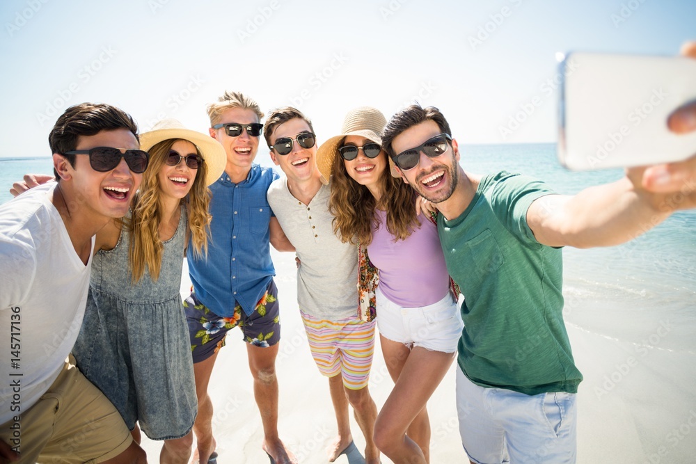 Cheerful young friends taking selfie at beach