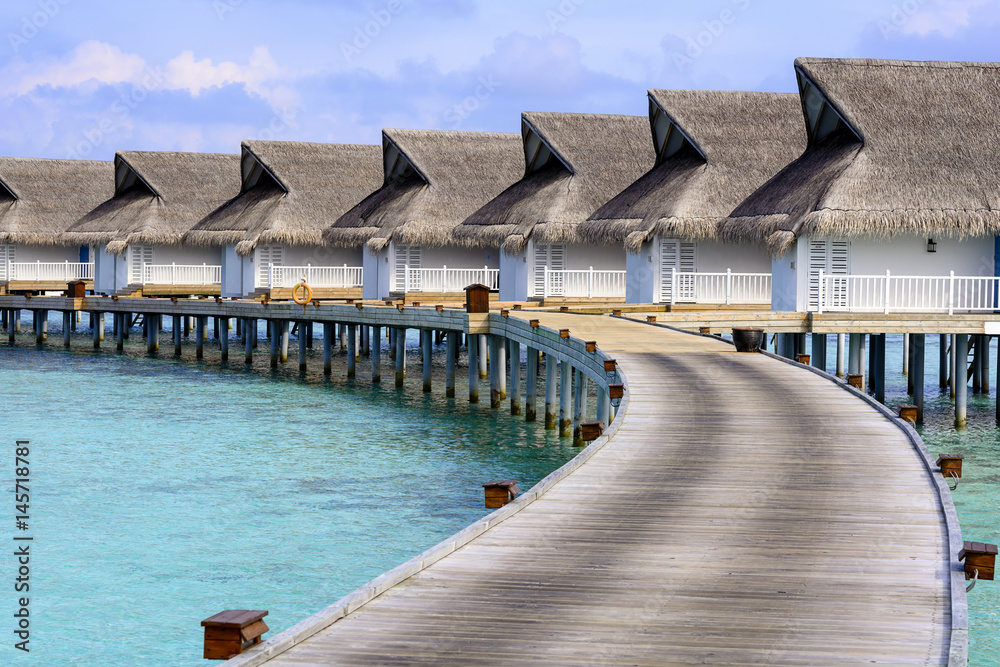 Wooden planks in the Maldives island  to a bungalow on the water and the beauty of the sea with the coral reefs