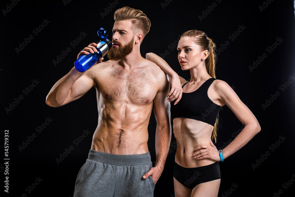 sportsman holding sport bottle and sportswoman  isolated on black