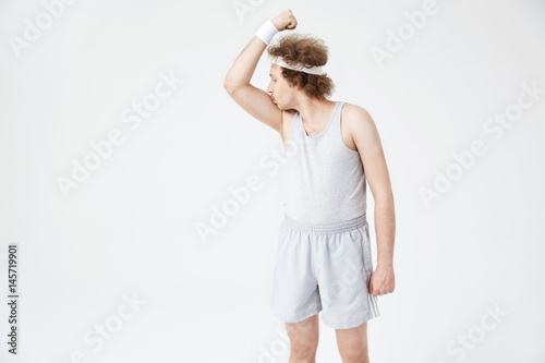 Retro guy with white headband kissing right arm biceps
