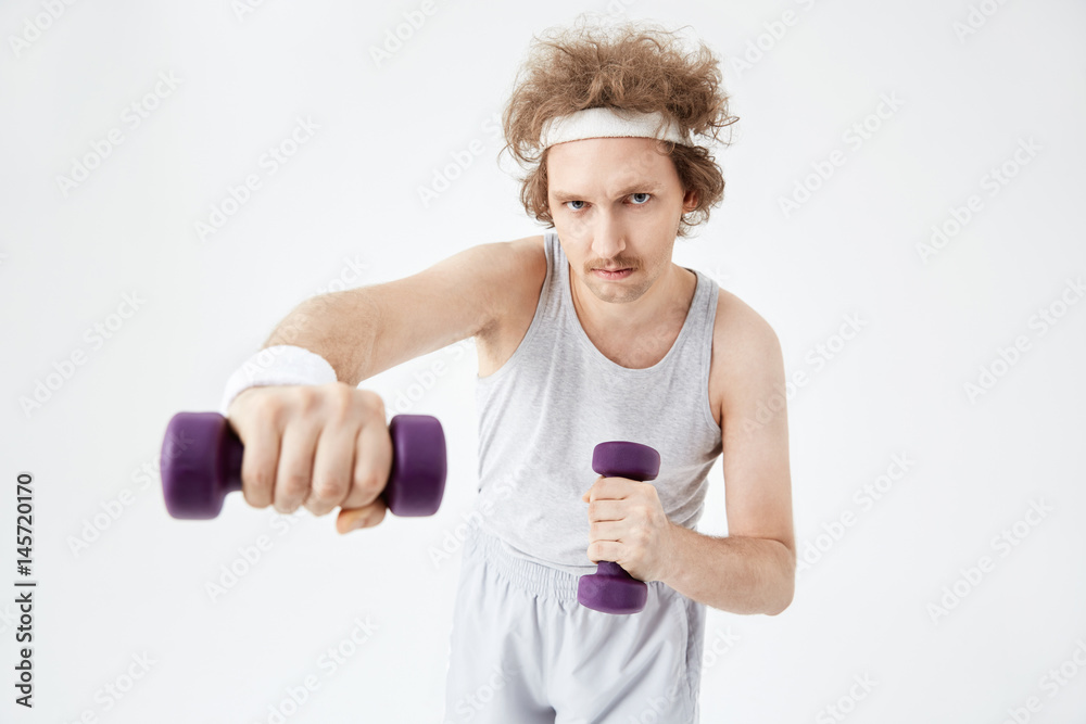 Young man working on arm muscles training with dumbbells Young man working on arm muscles training with dumbbells