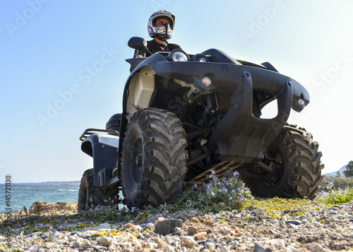 A man riding ATV in sand in a helmet.