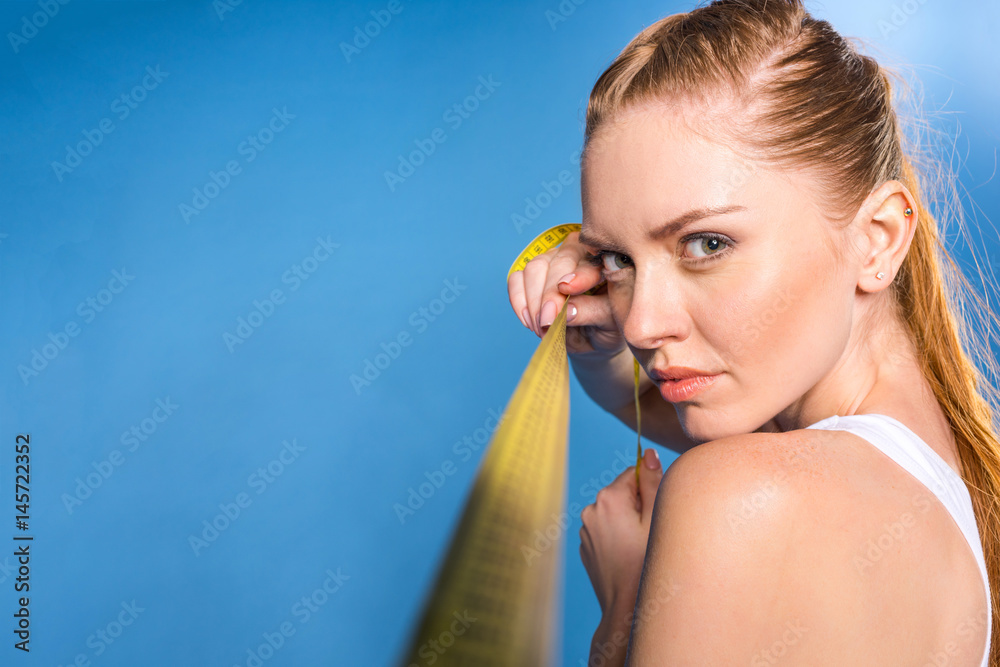 young sportswoman in white underwear with measuring tape isolated on blue in studio young sportswoman in white underwear with measuring tape isolated on blue in studio