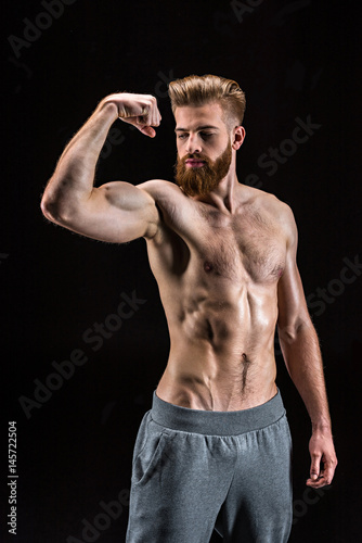 handsome bearded sportsman gesturing and standing isolated on black in studio