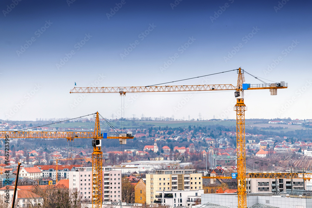 Industrial background with construction cranes over blue sky