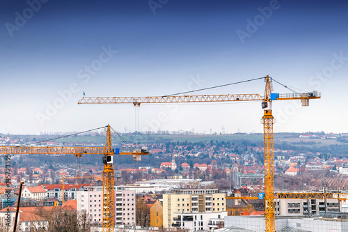 Industrial background with construction cranes over blue sky