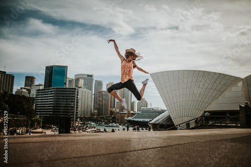 Happy woman jumping in the air in Sydney, with the cityscape in the background. Australia.