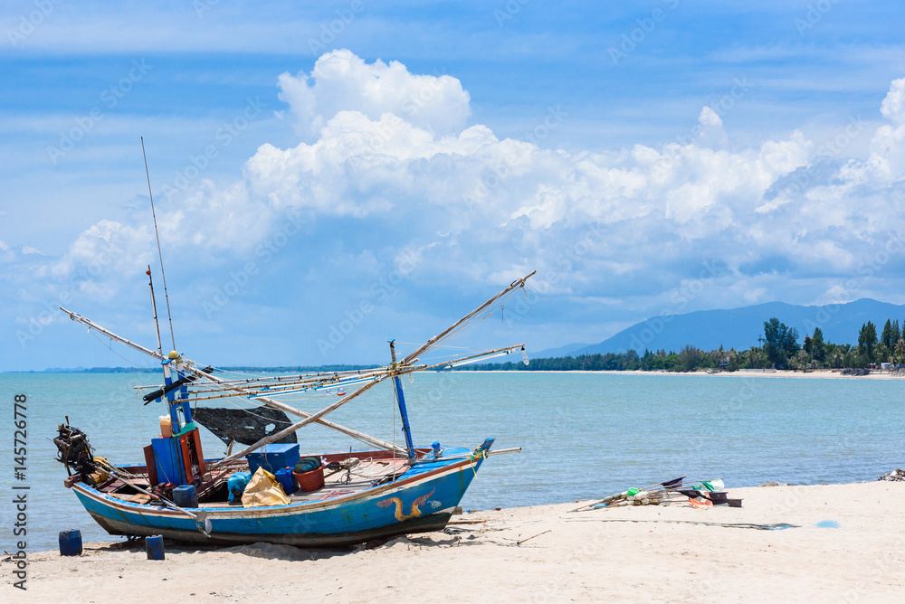 Fishing boats aground on the beach over cloudy sky at Prachuap Khiri Khan, Thailand.