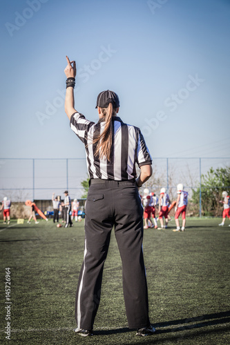 Foto Female American football referee and blurred players in the background