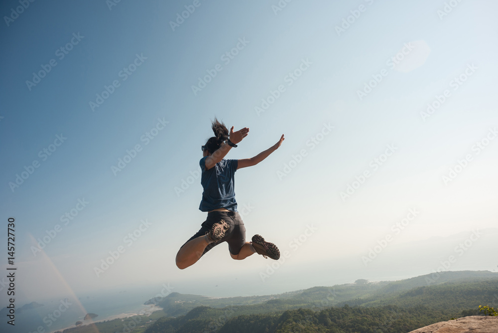 jumping on rocky mountain peak, freedom, risk, challenge, success concept jumping on rocky mountain peak, freedom, risk, challenge, success concept