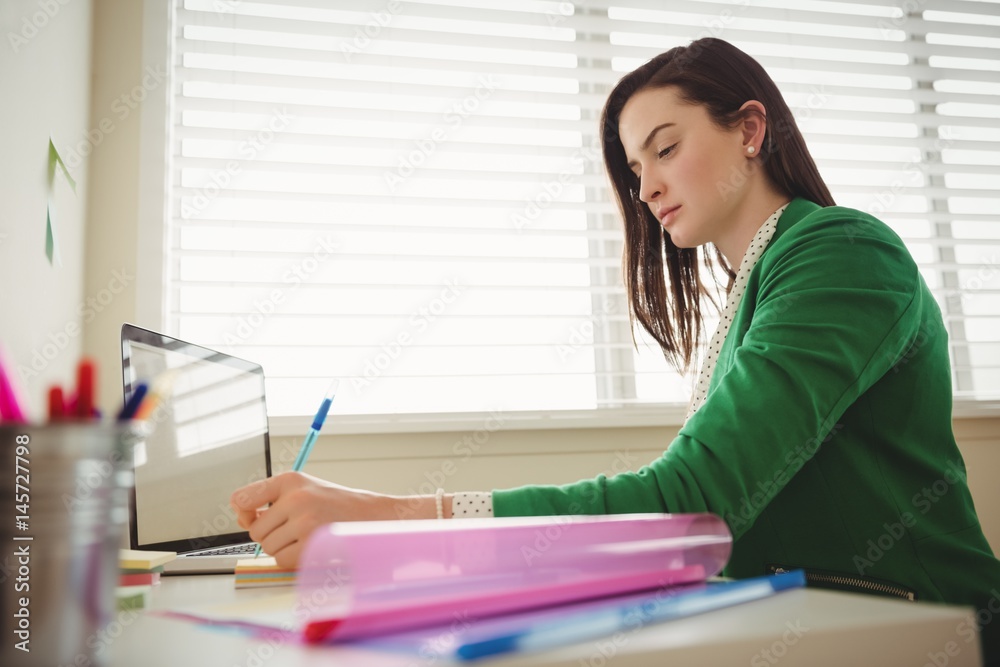 Side view of woman writing while sitting at table Side view of woman writing while sitting at table