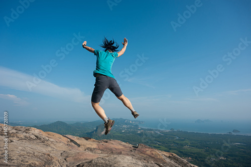 jumping on rocky mountain peak  freedom  risk  challenge  success concept