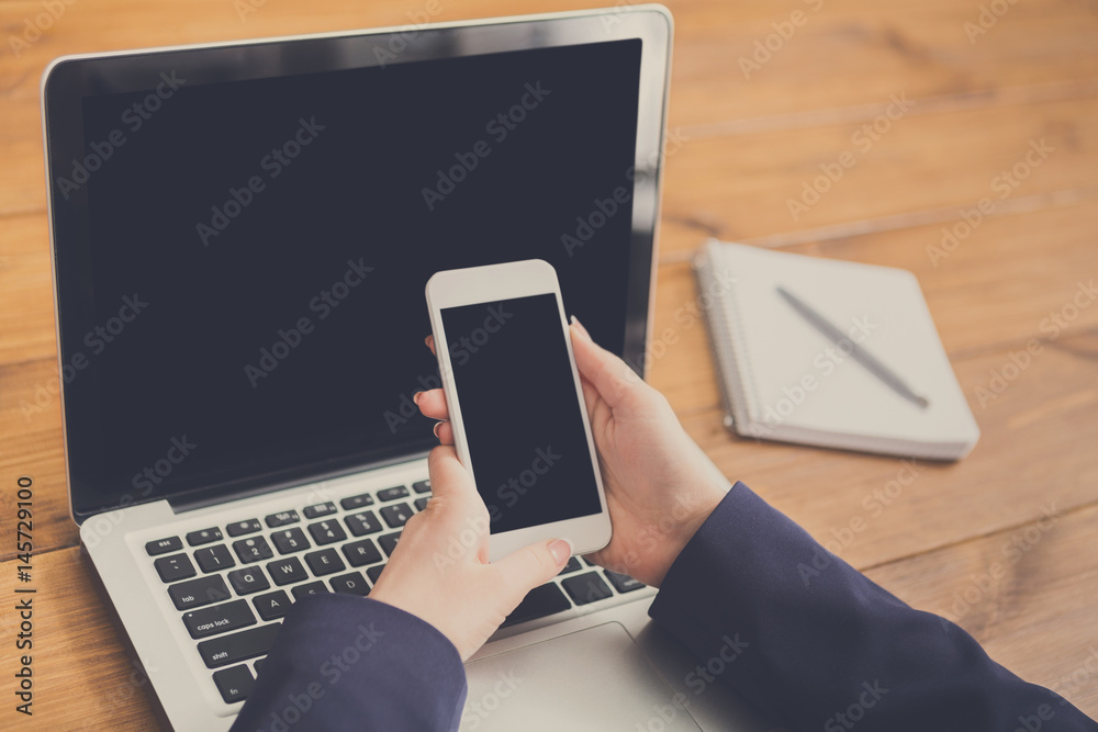Close-up of woman using laptop and smartphone