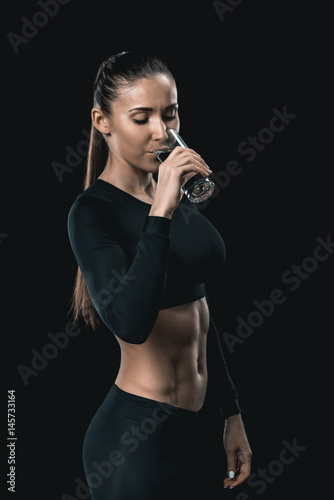 Young athletic woman in sportswear drinking water, healthy living concept © LIGHTFIELD STUDIOS