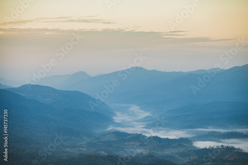 Beautiful autumnal landscape with sunrise over a foggy valley and mountain ranges.