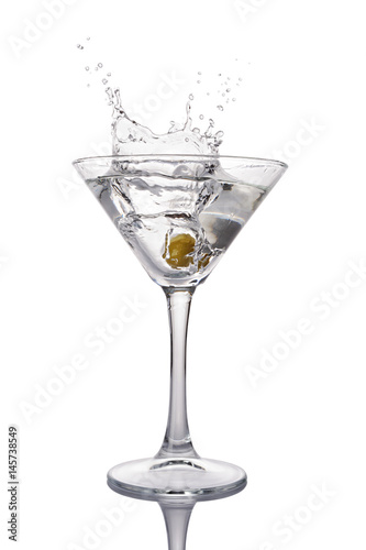 Splash in martini glass of white transparent alcoholic cocktail drink with olive