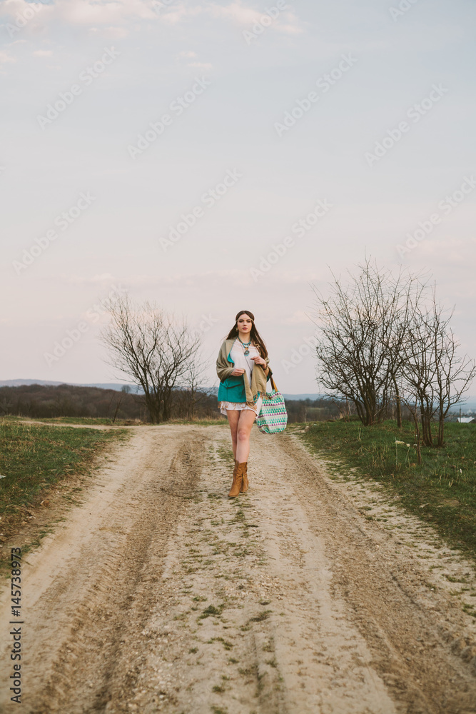 Obraz premium Hipster girl standing on a dirt road