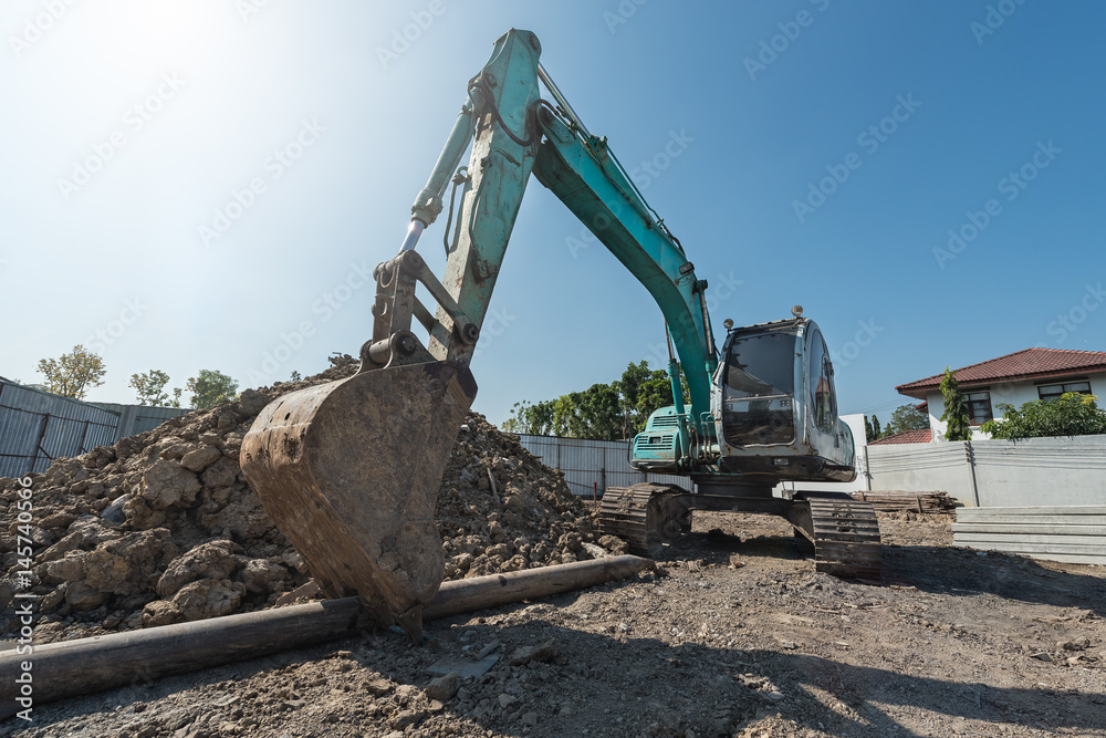excavator on construction site, digger on gravel heap with shovel