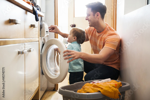Photo Father and toddler son doing laundry at home