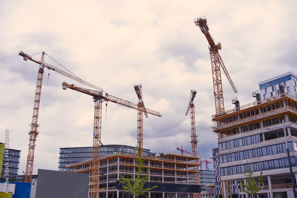 Housing development with cranes and clouds