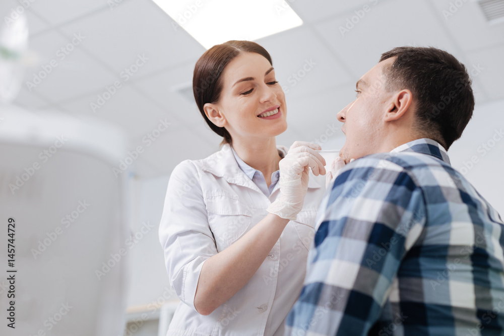 Smiling doctor examining sore throat