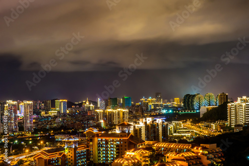 Night cityscape with clouds illuminated with city lights. Sanya town, Hainan Island of China.