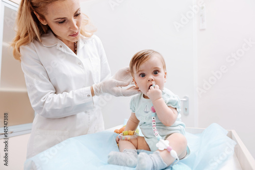 Attentive pediatrician examining ear of infant child
