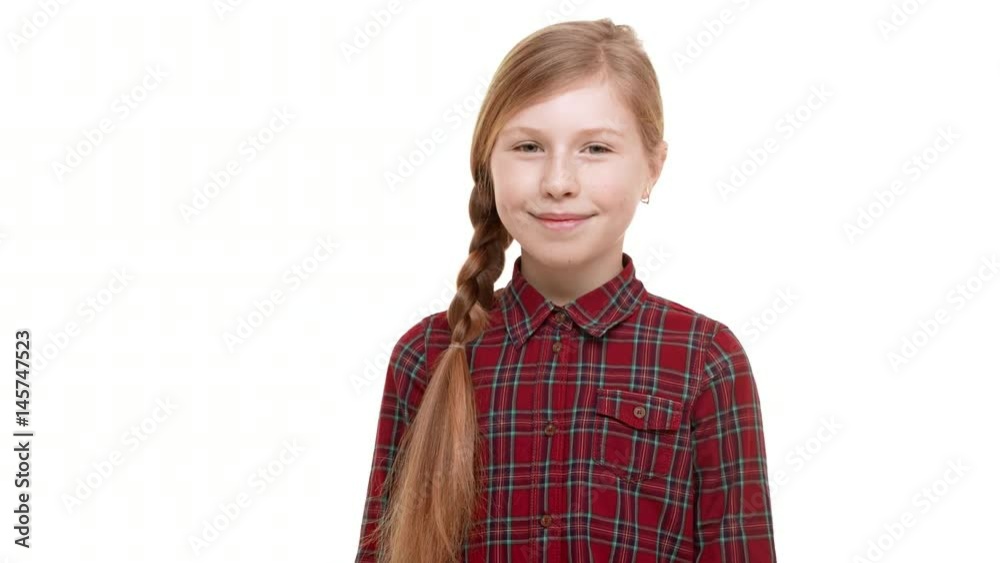 Cute elementary-school aged girl with light brown plait of hair standing on white background and smiling Cute elementary-school aged girl with light brown plait of hair standing on white background and smiling