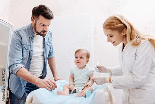 Scared child sitting between father and nurse