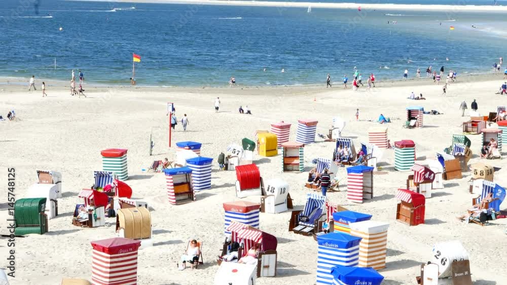 Strand mit Strandkörben und Surfern auf Nordsee Insel vor blauen Himmel