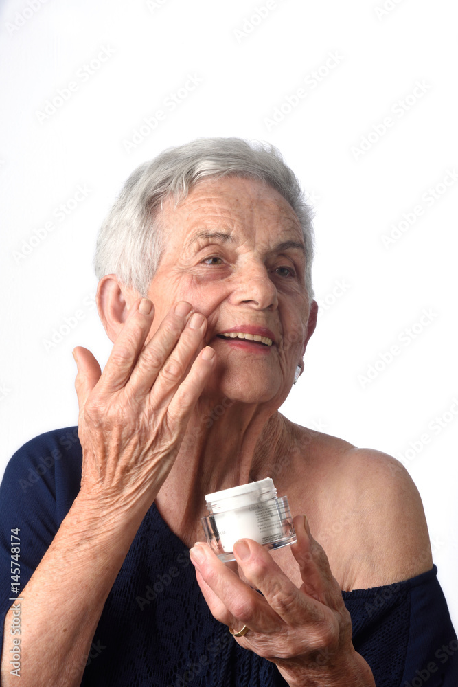 Senior woman applying skin cream or moisturiser to her face Senior woman applying skin cream or moisturiser to her face