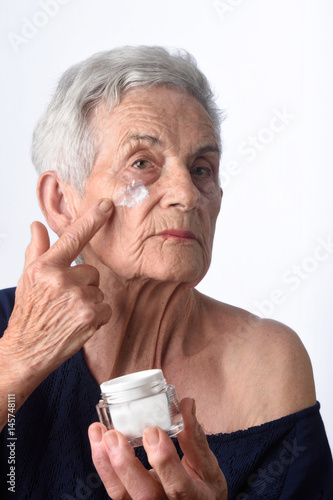 Senior woman applying skin cream or moisturiser to her face