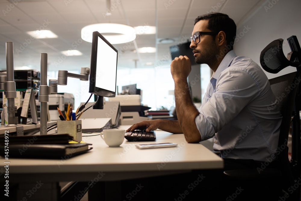 Thoughtful businessman working on computer in office Thoughtful businessman working on computer in office